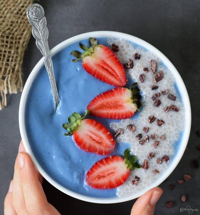 Blue coconut yogurt bowl with chia pudding, cacao nibs and strawberies. 