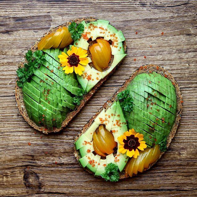 Bread with avocado, tomatoes, edible flowers, parsley, a squeeze of lime juice and smoked paprika sea salt